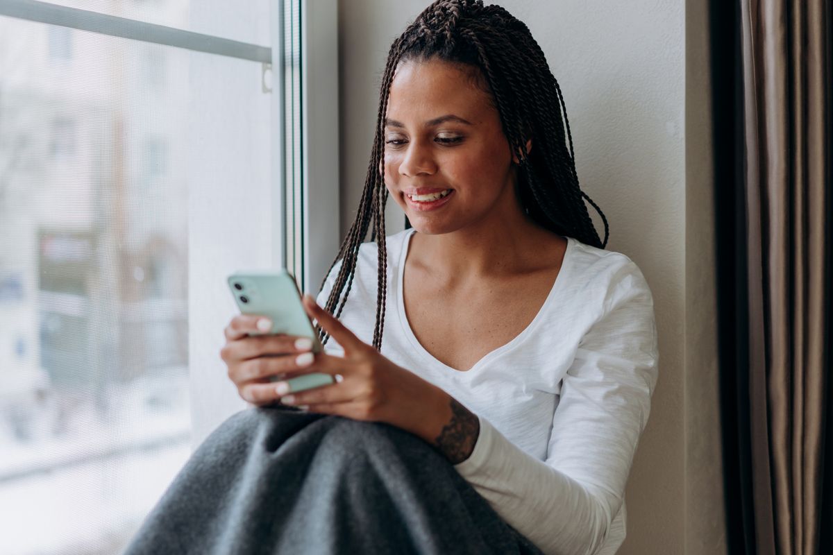 Someone reading a warm reply on their phone in natural window light